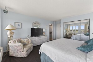 A hotel room with a bed, a television, a dresser, a chair, a lamp, and a mirror. - Corner Unit w/Sunrise & Sunset Views!| Pool | 1307 (Virginia Beach)