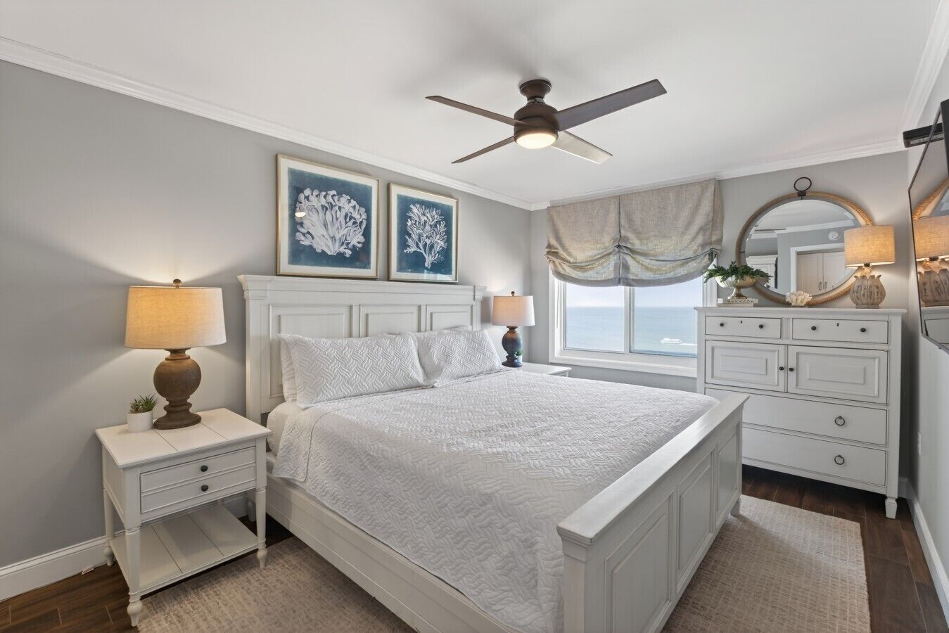 A bedroom with a bed, nightstands, a dresser, a ceiling fan, and artwork on the wall.