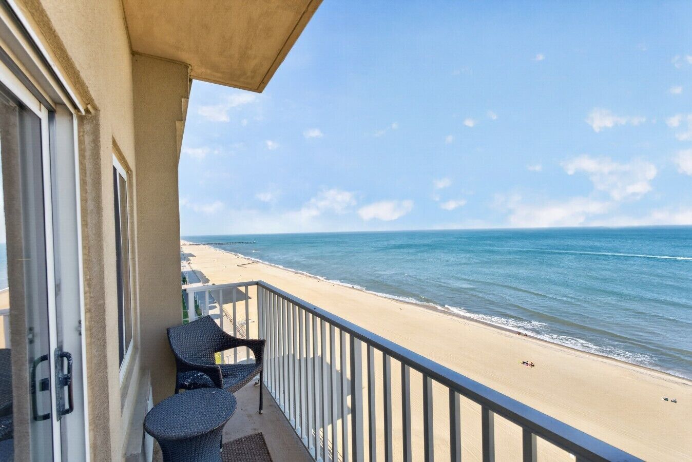 A balcony with a view of the beach and ocean.
