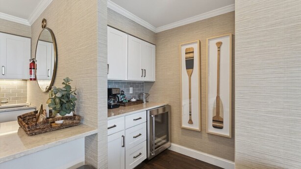 A kitchen with white cabinets, a coffee maker, and a toaster. There is a fire extinguisher mounted on the wall and a framed paddle on the wall.
