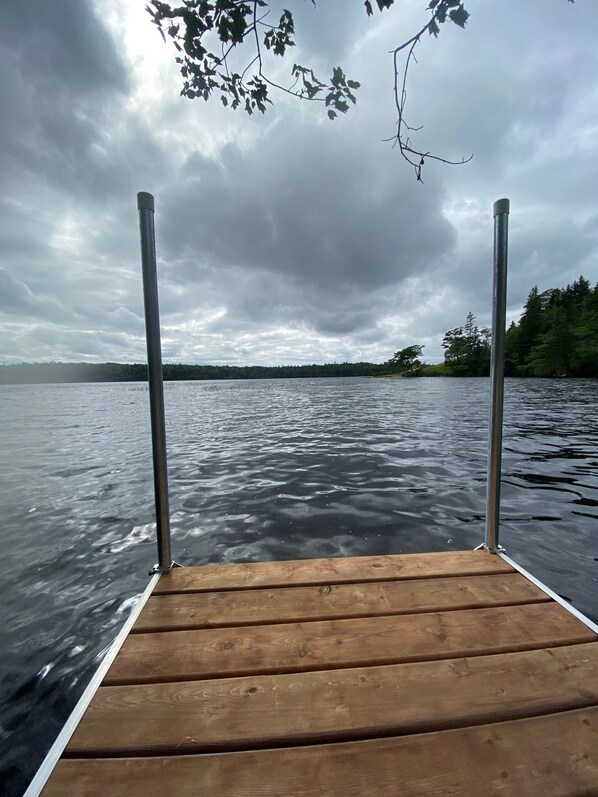 A wooden dock extending into a calm lake with a cloudy sky above.