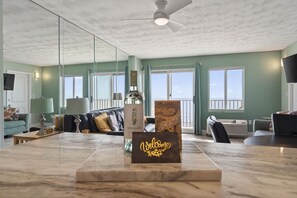 A spacious living area with a marble coffee table, a sofa, and a view of the sea through large windows.