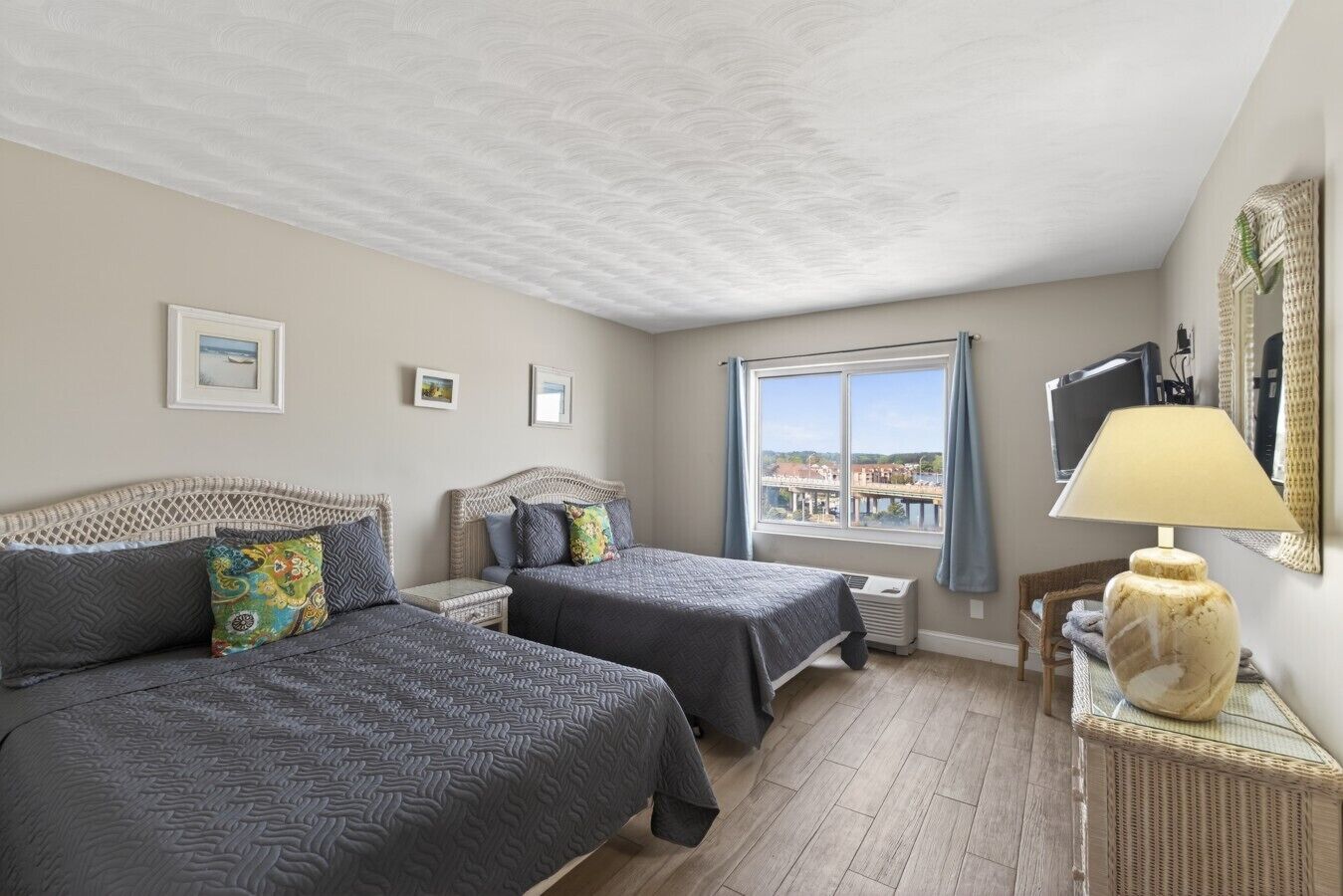 Une chambre avec deux lits, une fenêtre donnant sur un beau paysage, une lampe et un téléviseur.