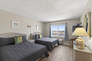 Ein Schlafzimmer mit zwei Betten, einem Fenster mit Ausblick, einer Lampe und einem Fernseher.