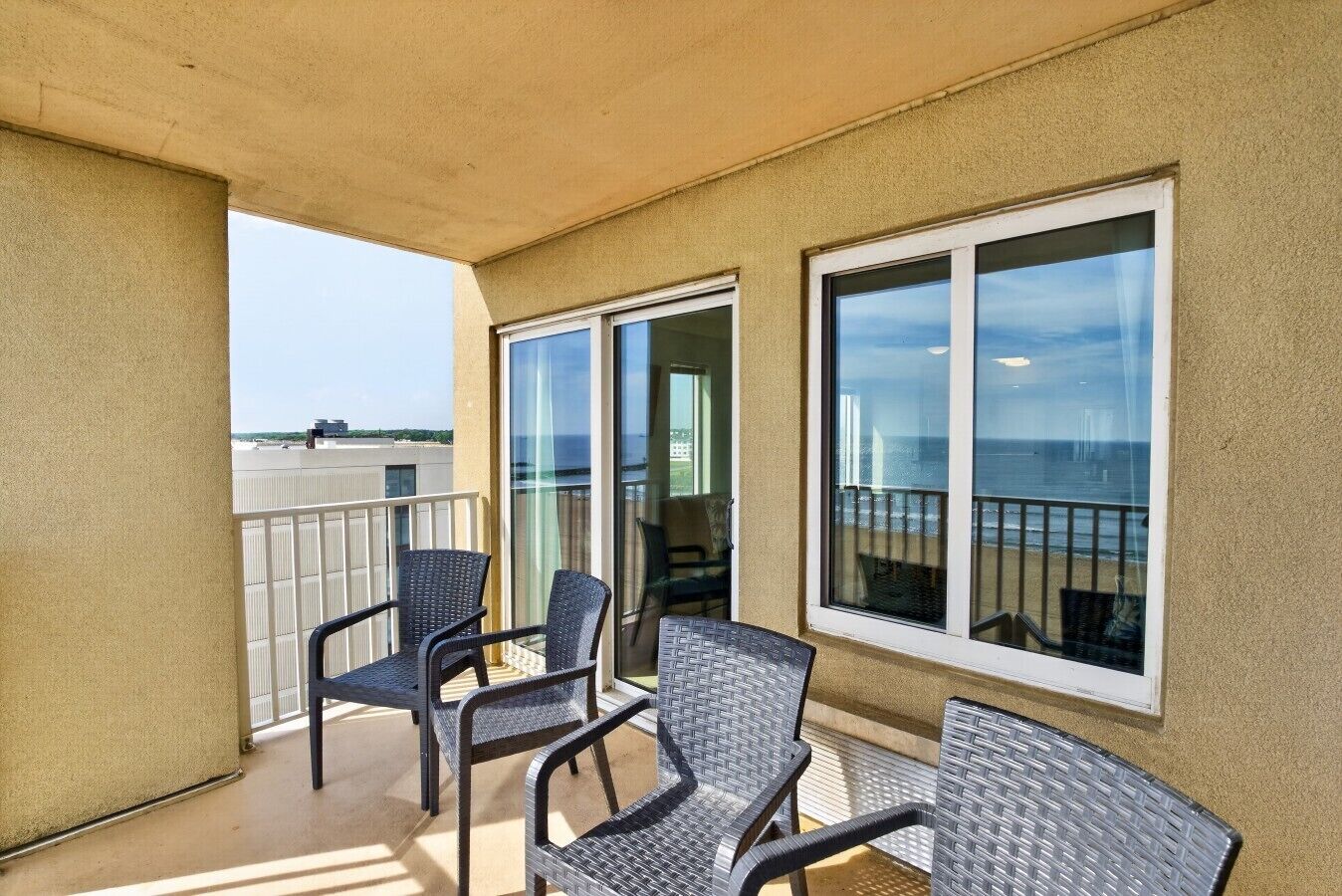 Un balcon avec une table et des chaises, donnant sur une plage et l’océan.