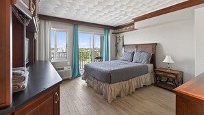 A hotel room with a bed, a nightstand, a window with curtains, and a view of the outside.