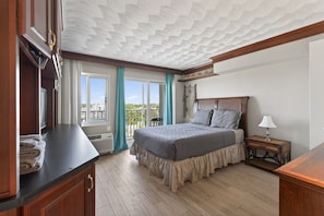 Habitación de hotel con cama, mesita de noche, ventana con cortinas y vistas al exterior.