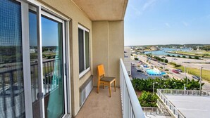 A balcony with a chair, overlooking a marina with boats and a parking area.