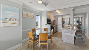 A modern kitchen with a central island, wooden chairs, and a dining table.