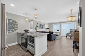 A modern kitchen with a central island, a dining area with a view, and a living room with a large window.