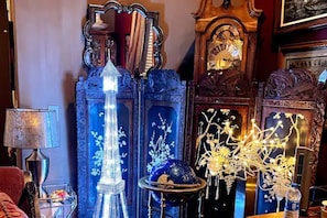 Una habitación con un espejo grande y ornamentado, un jarrón azul alto y un candelabro decorativo.