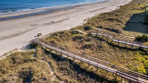 A beach with a wooden boardwalk, sandy beach, and ocean. - Beach Nest 2 Stylish Condo  2 Min Walk to Beach (North Myrtle Beach)