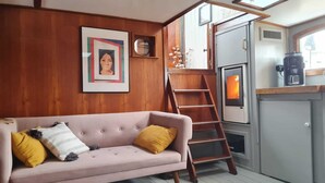 Ein gemütliches Wohnzimmer mit einem rosafarbenen Sofa, Holzwänden, einer Leiter und einer Kaffeemaschine.