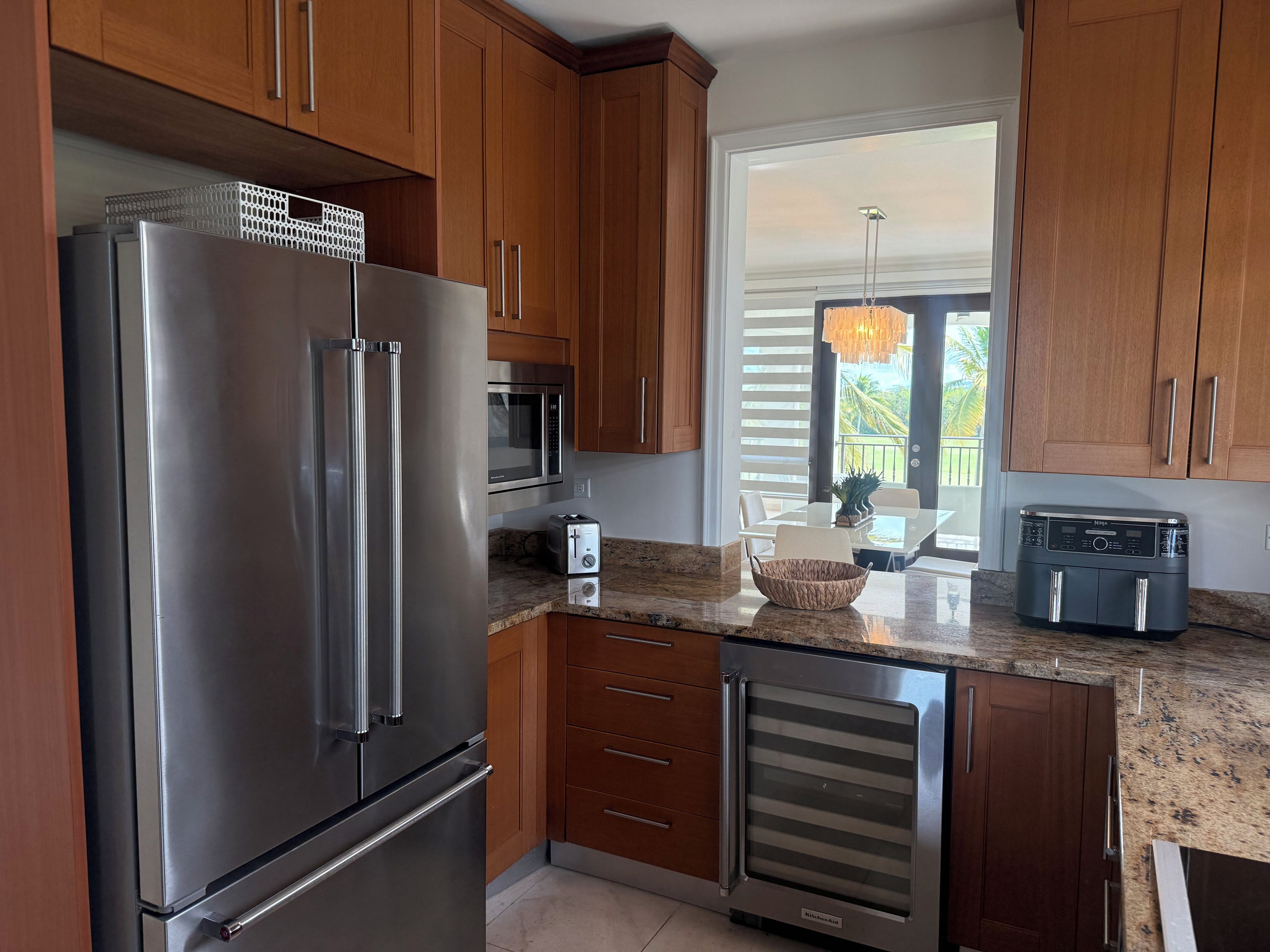 A modern kitchen with stainless steel appliances, wooden cabinets, and a granite countertop.