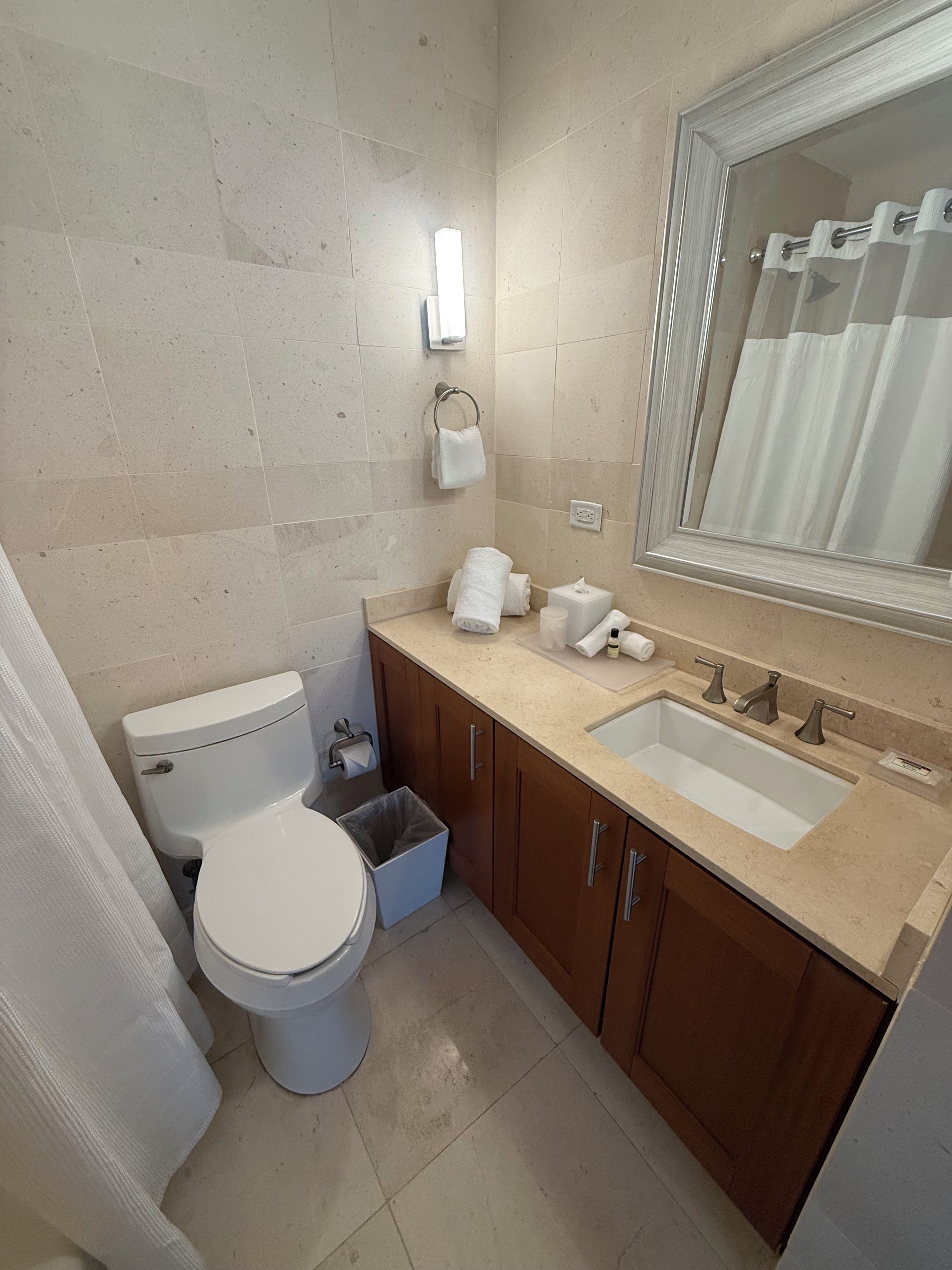 Et badeværelse med toilet, vask, spejl og håndklædetørrestativ.