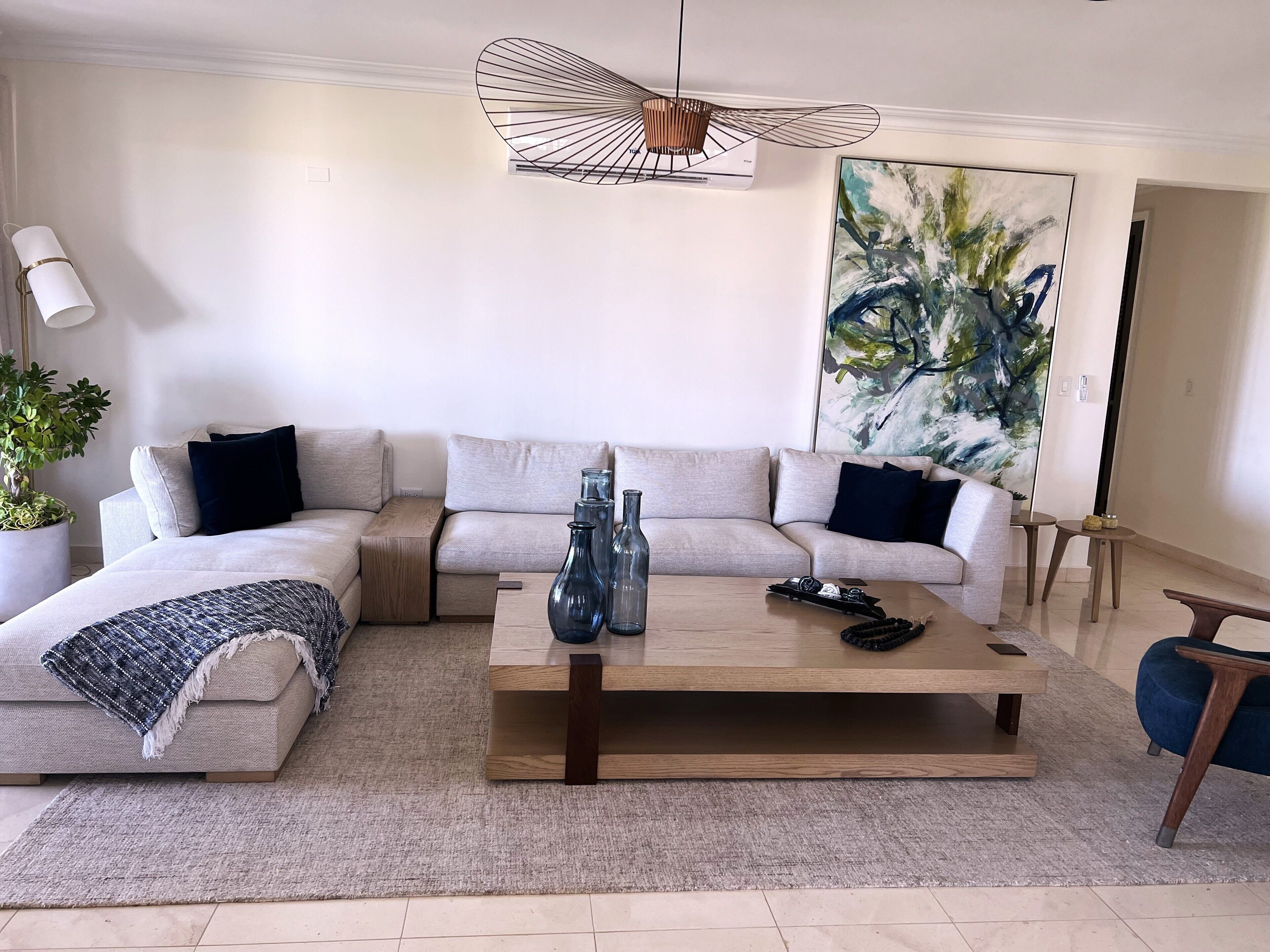 Ein modernes Wohnzimmer mit einem Ecksofa, einem Couchtisch und einem großen abstrakten Gemälde.