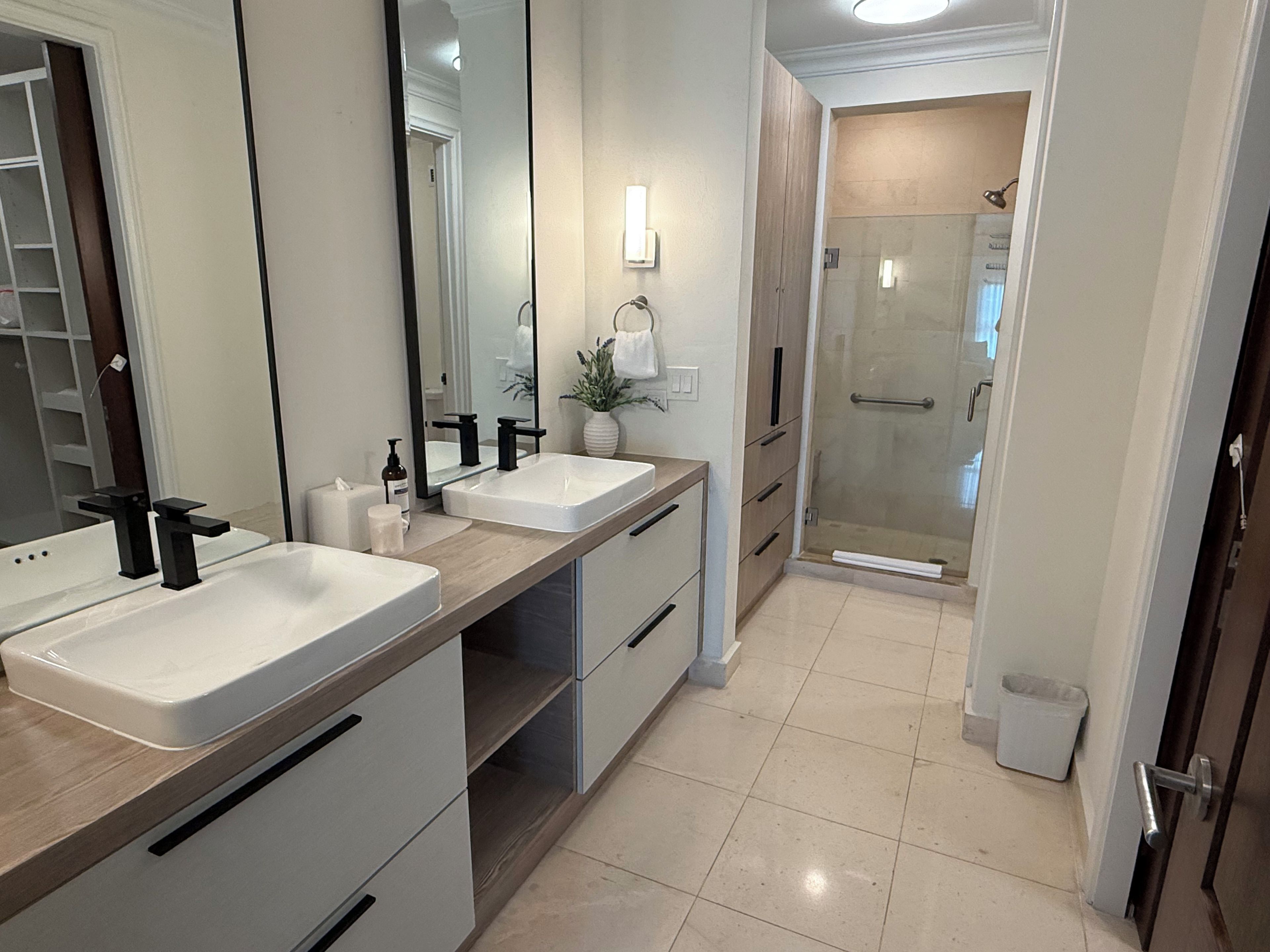 Casa de banho moderna com duas pias, espelho e zona de duche.