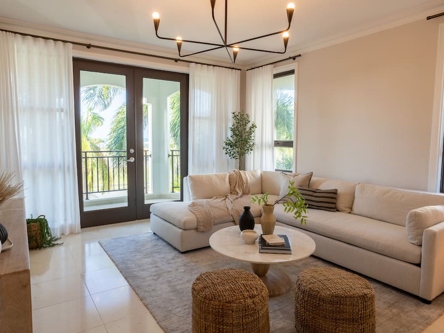 Una sala de estar moderna con un sofá color beige, una mesa de centro redonda y un ventanal con cortinas.
