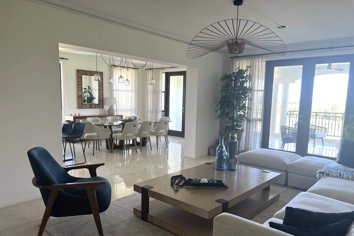 Ein geräumiges Wohnzimmer mit einer modernen Couch, einem Couchtisch und einem Essbereich mit Stühlen und einem Tisch.