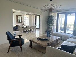 A spacious living room with a modern sofa, a coffee table, and a dining area with chairs and a table.