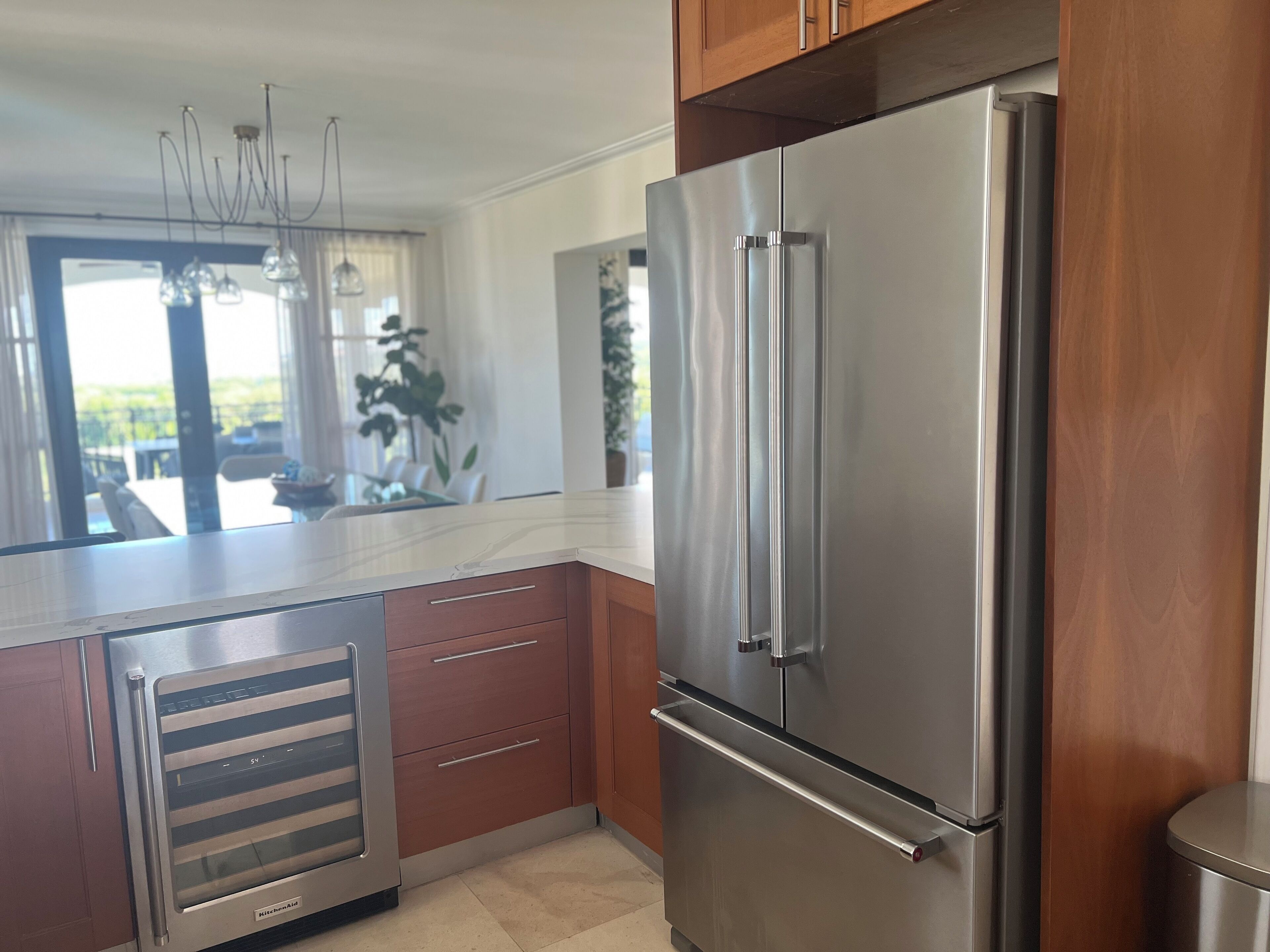 A kitchen with a stainless steel refrigerator, wooden cabinets, a marble countertop, and a built-in oven.