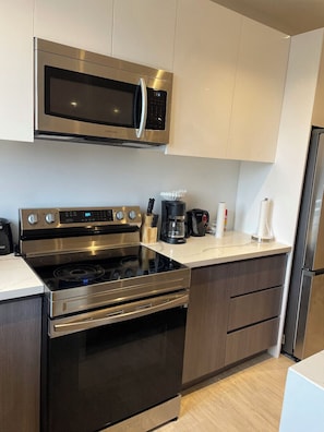Enjoy cooking in this sleek kitchen with a microwave, oven, and coffee maker.