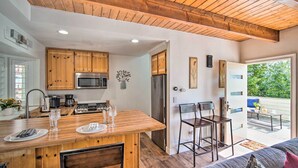A modern kitchen with wooden cabinets, a central island, and a dining area with chairs. - Crestline Cabin w/ Deck: 1 Mi to Lake Gregory (Crestline)