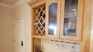 A kitchen with a granite countertop, a decorative bowl, a wine rack, and a cabinet with glass doors. - Pet Friendly - Overlooks Pool - Sleeps Tons (South Padre Island)