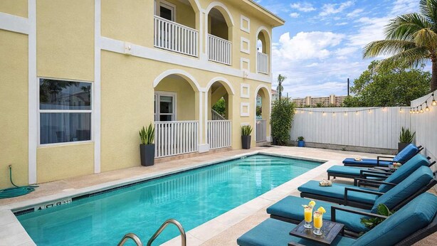 A swimming pool with lounge chairs and a two-story building with balconies. - Pet Friendly - Overlooks Pool - Sleeps Tons (South Padre Island)