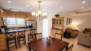 A modern kitchen with a dining area, a chandelier, and a living room with a sofa and armchair. - Pet Friendly - Overlooks Pool - Sleeps Tons (South Padre Island)