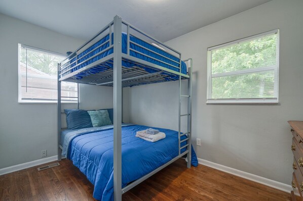 A bunk bed with blue bedding, a wooden dresser, and a window with blinds. - 3BR Hampton Home, Central to HU, and Colosseum! (Hampton)