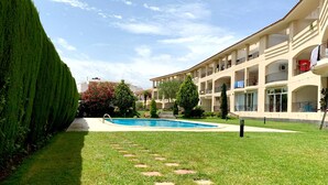 A hotel courtyard with a swimming pool, neatly trimmed grass, and a variety of trees. - Apartment in Clota Petita, L´Escala, 2 minutes from the beach! (L'Escala)