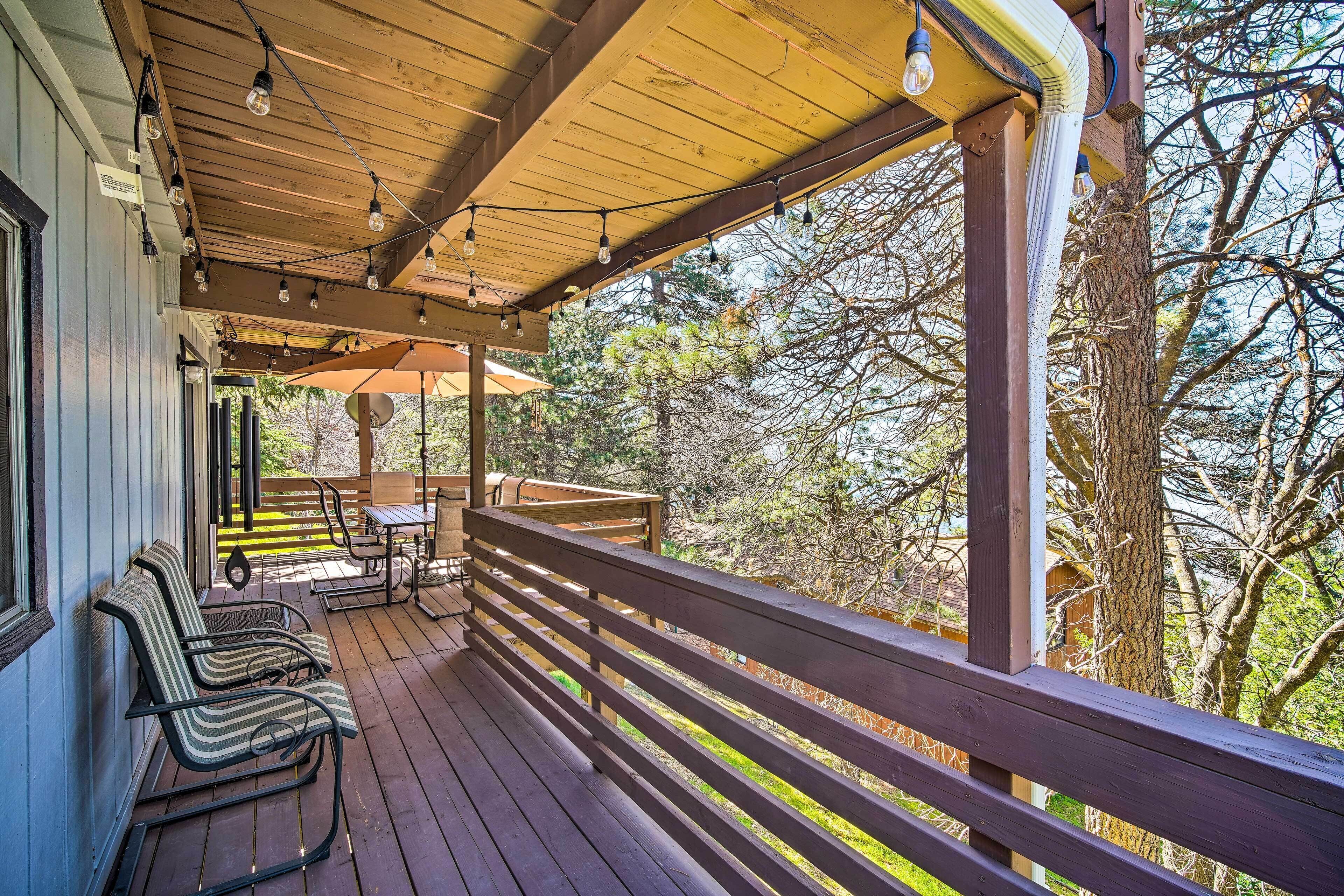 A wooden deck with outdoor seating and a covered area with string lights.