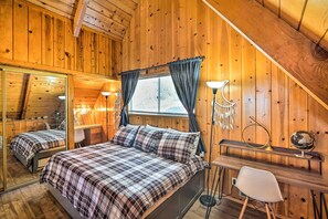 A cozy wooden cabin room with a bed, a desk, and a chair.