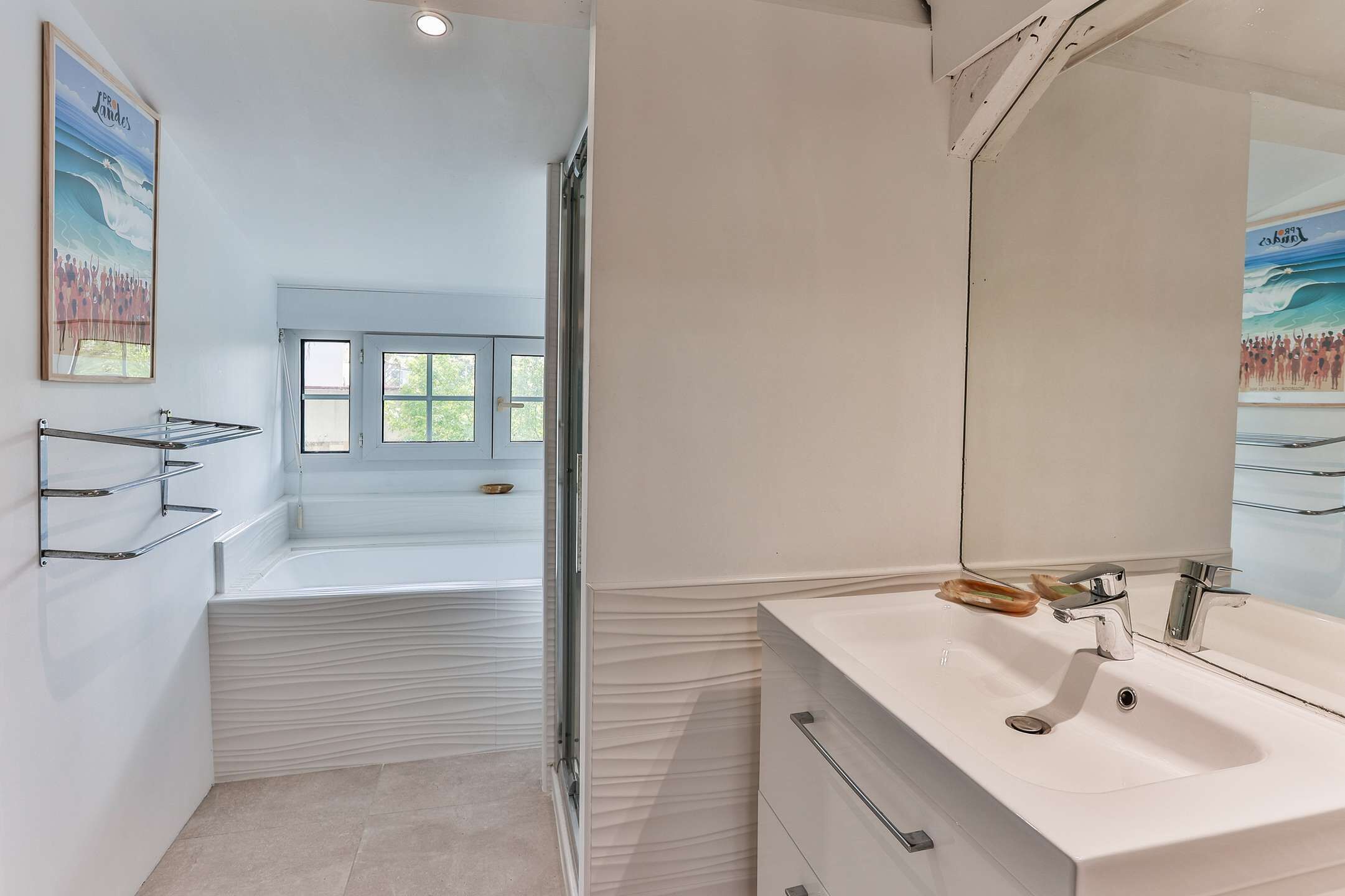 Un baño moderno con un espejo grande, un lavamanos blanco y una bañera.
