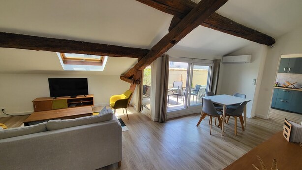 A loft-style living room with a wooden ceiling, a sofa, a TV, and a dining area with a table and chairs. - La Dolce Vita Nîmoise 🐊 Terrace 100 m from the Arena (Nîmes)