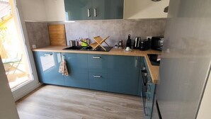 A modern kitchen with blue cabinets, a stainless steel refrigerator, and a wooden floor. - La Dolce Vita Nîmoise 🐊 Terrace 100 m from the Arena (Nîmes)