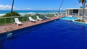 Una piscina con sillas de descanso blancas y vistas al océano.