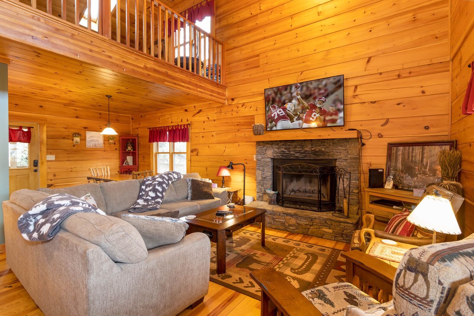 A cozy cabin interior with a fireplace, a sofa, and a television mounted above it.