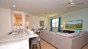 A compact living space with a kitchen, dining area, and a sofa. - Pool Home in Gated Golf Community With Game Room & Themed Kid's Rooms (Davenport)