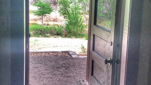 An open door leading to a garden with a concrete path and a rug.