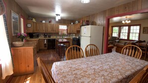 A cozy kitchen with wooden cabinets, a dining table with chairs, and a refrigerator.