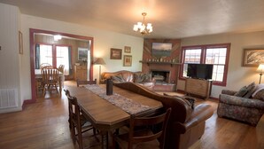 A cozy living room with a wooden dining table, chairs, a sofa, and a television.