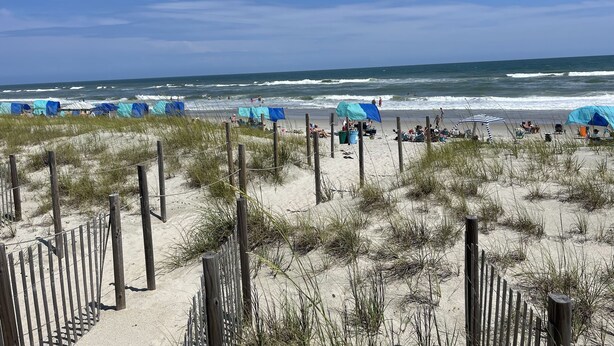 Een strand met tenten en een houten omheining.