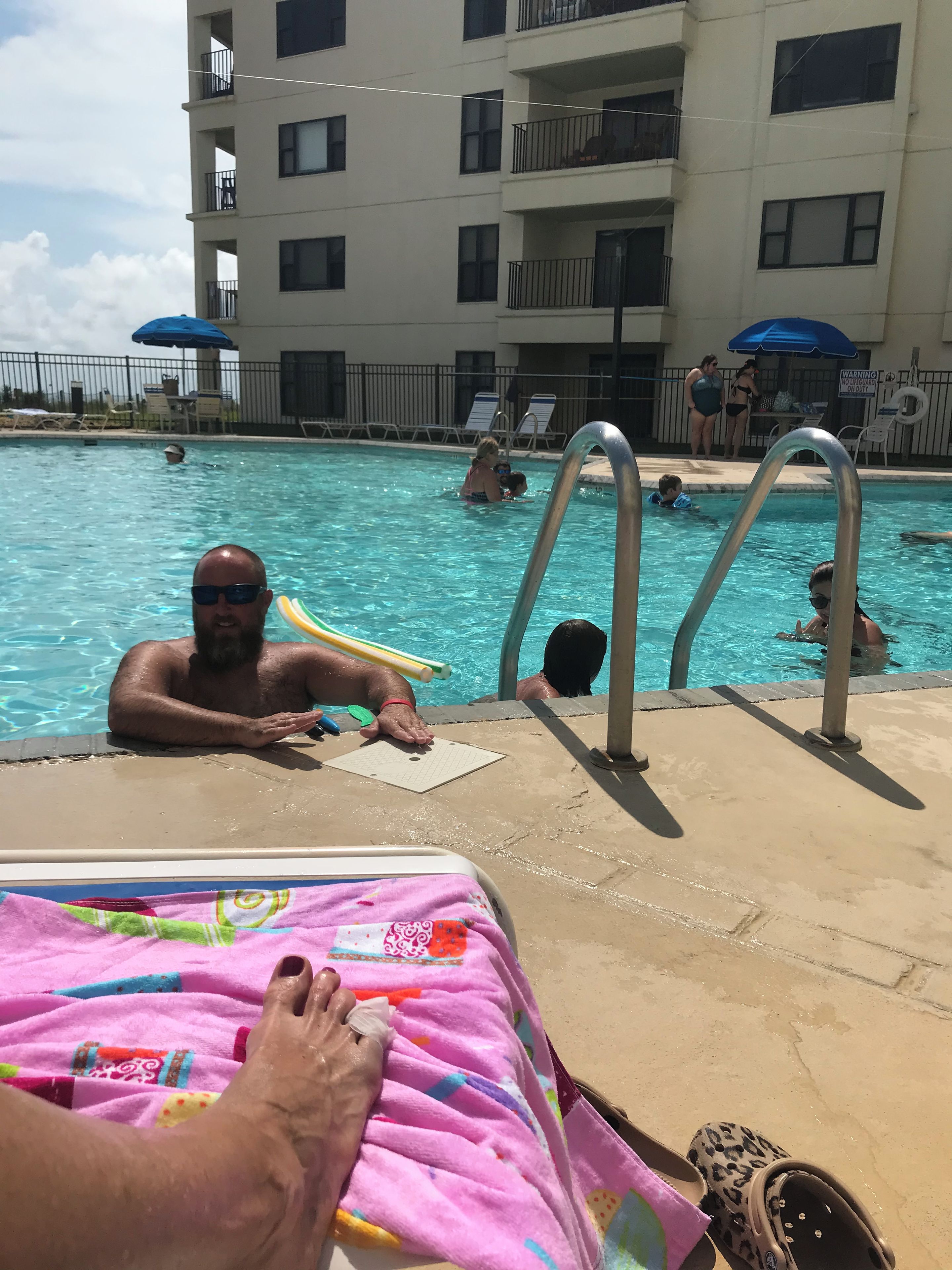 A swimming pool area with lounge chairs and umbrellas.