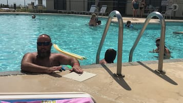 A swimming pool area with lounge chairs and umbrellas.