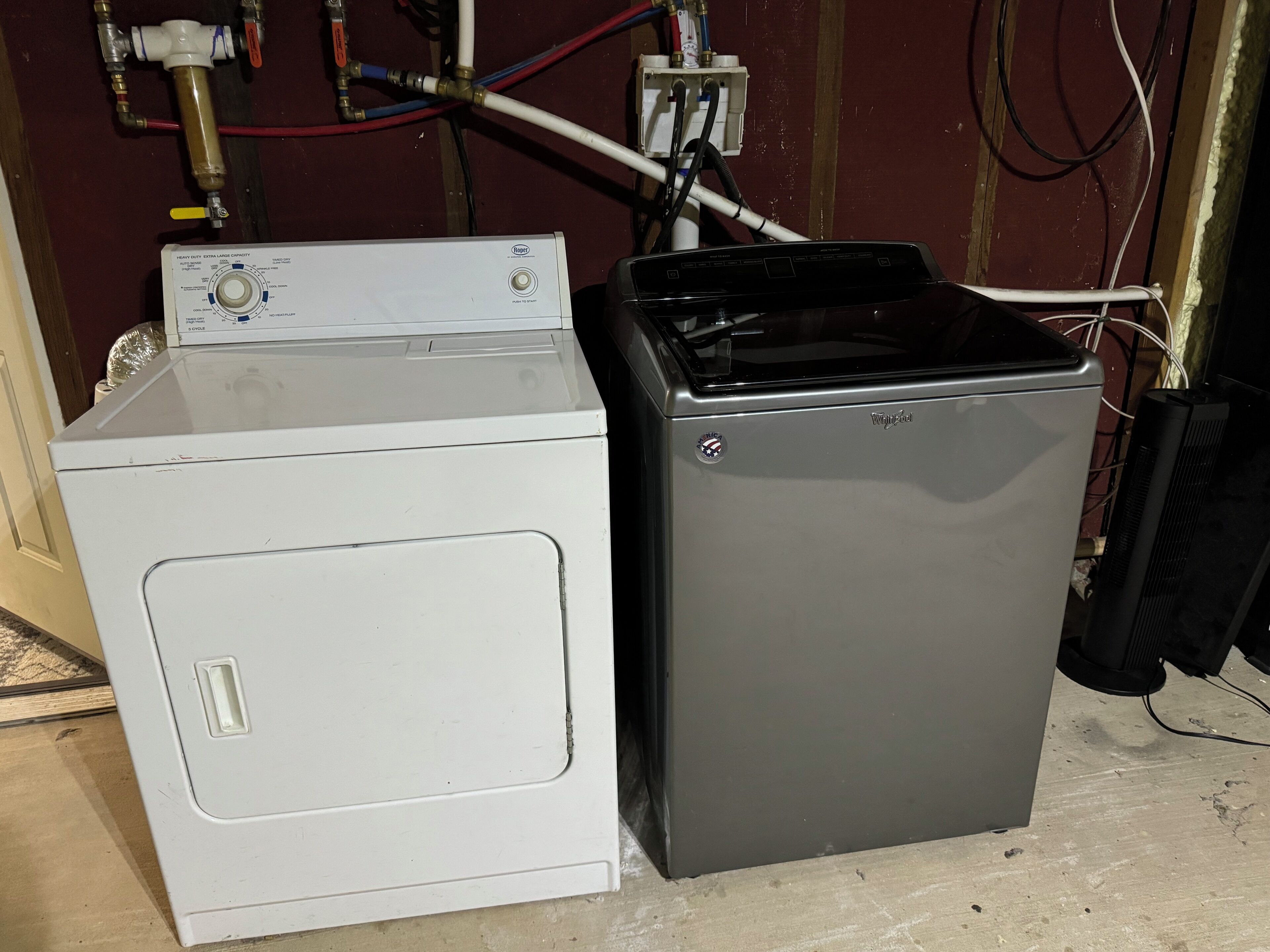 Une petite buanderie équipée d’un lave-linge blanc et d’un réfrigérateur gris.