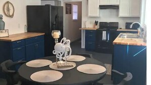 Una cocina moderna con armarios blancos, un refrigerador negro y un comedor con una mesa redonda y sillas.