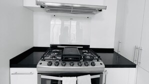 A compact kitchen with a stove, oven, and white cabinets. - House at the Historical Arcos de Oaxaca (Oaxaca De Juarez)