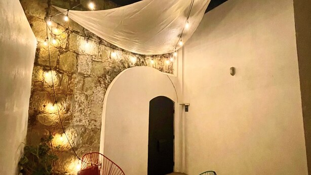 An outdoor patio with stone walls, a white canopy, string lights, and modern chairs. - House at the Historical Arcos de Oaxaca (Oaxaca De Juarez)